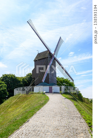 Traditional windmill on grassy hill with cobblestone path 138593194