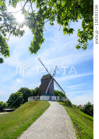 Wooden windmill on grassy hill under blue sky Wooden windmill on grassy hill under blue sky 138593196