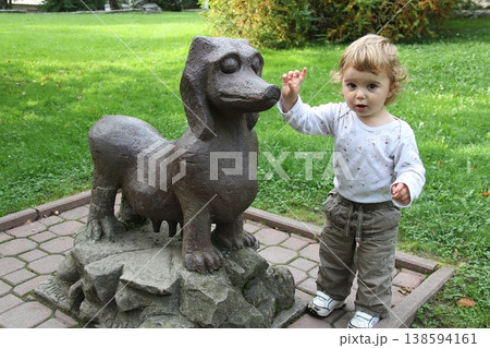 Toddler Standing Next to Dog Statue in Park Toddler Standing Next to Dog Statue in Park 138594161