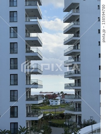High-rise residential buildings with balconies and view of distant houses, sky, and clouds 138594780