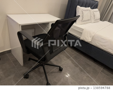 Home office setup with black chair at white desk in modern bedroom, suitable as a background Home office setup with black chair at white desk in modern bedroom, suitable as a background 138594788