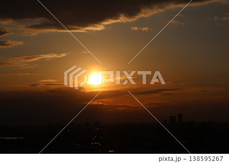 オレンジ色の夕陽と夕空とシルエットの雲と街並みの風景 138595267