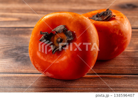 Two fresh ripe persimmons on a rustic wooden table background Two fresh ripe persimmons on a rustic wooden table background 138596407