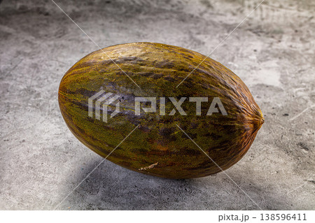 Single whole Piel de Sapo melon on a textured gray stone background 138596411