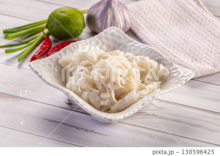 Cooked rice noodles in a white bowl with fresh lime, garlic, and chili peppers 138596425