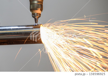 Close-up of a high-precision fiber laser cutting machine engraving a stainless steel tube with bright sparking light. Close-up of a high-precision fiber laser cutting machine engraving a stainless steel tube with bright sparking light. 138596925