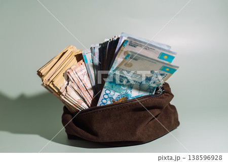 Kazakhstani tenge banknotes stacked in a brown pouch on green background, cash savings concept Kazakhstani tenge banknotes stacked in a brown pouch on green background, cash savings concept 138596928