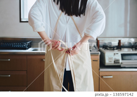 キッチンでエプロンをつける女性 家事や料理準備の生活シーン キッチンでエプロンをつける女性 家事や料理準備の生活シーン 138597142