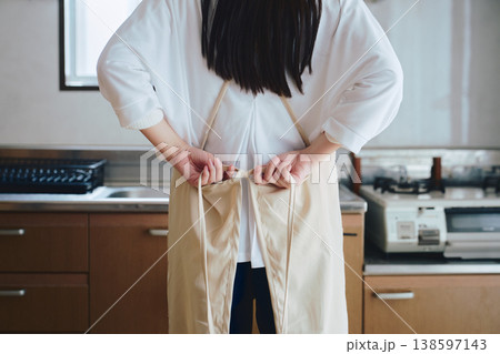 キッチンでエプロンをつける女性 家事や料理準備の生活シーン キッチンでエプロンをつける女性 家事や料理準備の生活シーン 138597143