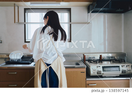 キッチンでエプロンをつける女性 家事や料理準備の生活シーン キッチンでエプロンをつける女性 家事や料理準備の生活シーン 138597145