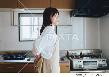 キッチンでエプロンをつける女性 料理前の準備シーン 138597256