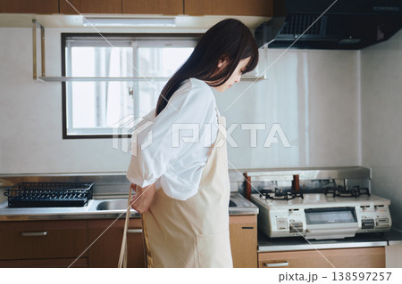 キッチンでエプロンをつける女性 料理前の準備シーン 138597257
