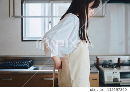 キッチンでエプロンをつける女性 料理前の準備シーン キッチンでエプロンをつける女性 料理前の準備シーン 138597260