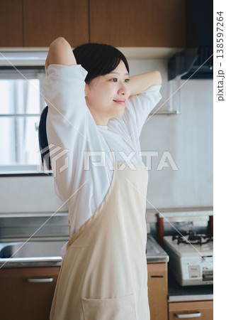 キッチンでエプロンをつける女性 料理前の準備シーン キッチンでエプロンをつける女性 料理前の準備シーン 138597264