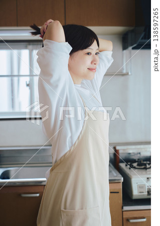 キッチンでエプロンをつける女性 料理前の準備シーン キッチンでエプロンをつける女性 料理前の準備シーン 138597265