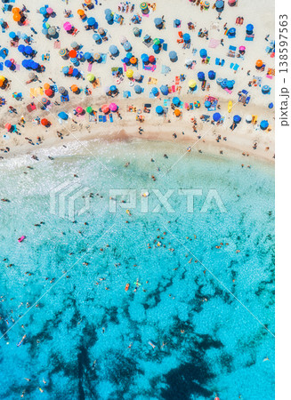 Aerial view of colorful umbrellas on sandy beach, swimming people Aerial view of colorful umbrellas on sandy beach, swimming people 138597563