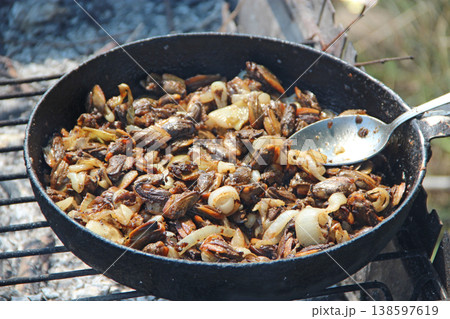 Cooking fried mussels in frying pan. Frying fresh mussels and onions Cooking fried mussels in frying pan. Frying fresh mussels and onions 138597619
