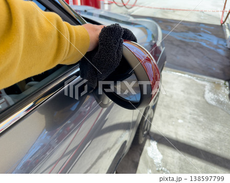 Man wiping and drying car with grey microfiber rag outdoors, closeup Man wiping and drying car with grey microfiber rag outdoors, closeup 138597799