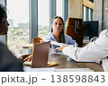 Woman Reviewing Documents. Woman Concentrates On Report While Coordinator Offers Approval Documents Nearby 138598843