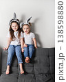 Two children in bunny ears sitting together on sofa in living room. Easter holiday, friendship, sibling relationship and family lifestyle concept. 138598880