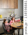 Two girls painting Easter eggs at table in kitchen 138598881