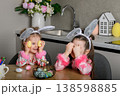 Two girls painting Easter eggs at table in kitchen 138598885