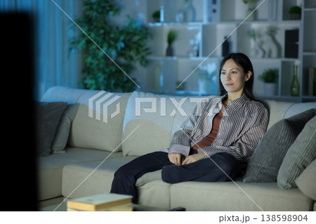 Serious asian woman watching tv at home in the night 138598904