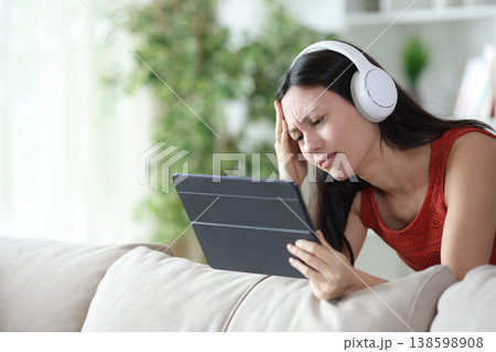Sad asian woman checking online content on tablet Sad asian woman checking online content on tablet 138598908