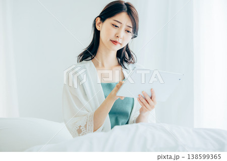 ベッドでタブレットを操作するミドルの女性 ベッドでタブレットを操作するミドルの女性 138599365