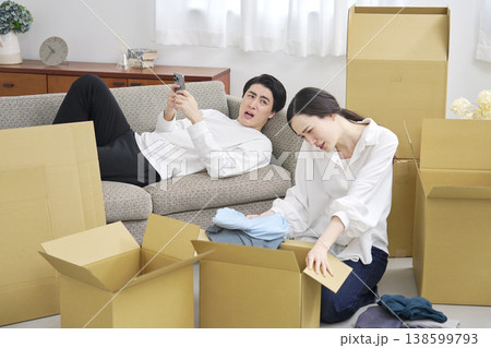 引っ越し作業中スマホを見る男性と疲れている女性 引っ越し作業中スマホを見る男性と疲れている女性 138599793