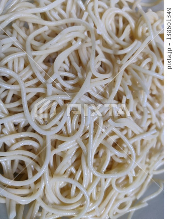 Close-up Image of Cooked Noodles Showing Twisted and Wavy Shapes Glistening in Natural Light on a White Plate Surface Close-up Image of Cooked Noodles Showing Twisted and Wavy Shapes Glistening in Natural Light on a White Plate Surface 138601349