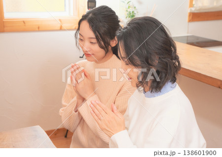 自宅で故人に祈りを捧げる母と娘（レトロ風） 138601900