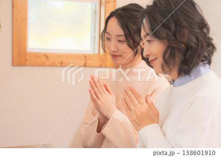 自宅で故人に祈りを捧げる母と娘(レトロ風) 自宅で故人に祈りを捧げる母と娘(レトロ風) 138601910