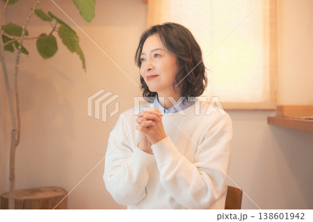 自宅で故人に祈りを捧げるミドル女性（レトロ風） 138601942