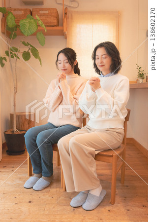 自宅で故人に祈りを捧げる母と娘(レトロ風) 自宅で故人に祈りを捧げる母と娘(レトロ風) 138602170