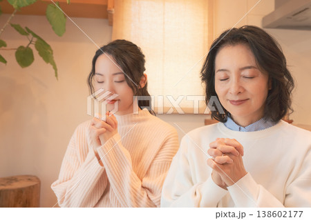 自宅で故人に祈りを捧げる母と娘(レトロ風) 自宅で故人に祈りを捧げる母と娘(レトロ風) 138602177