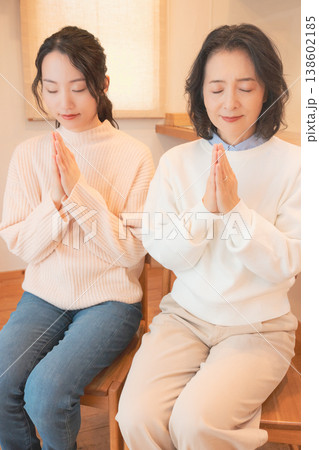 自宅で故人に祈りを捧げる母と娘(レトロ風) 自宅で故人に祈りを捧げる母と娘(レトロ風) 138602185
