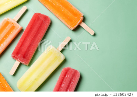 Colorful fruit popsicles on green background Colorful fruit popsicles on green background 138602427