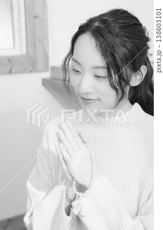 自宅で故人に祈りを捧げる娘（モノクロ） 138603101