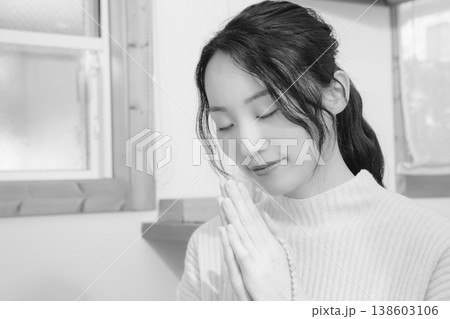 自宅で故人に祈りを捧げる娘(モノクロ) 自宅で故人に祈りを捧げる娘(モノクロ) 138603106
