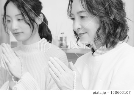 自宅で故人に祈りを捧げる母と娘(モノクロ) 自宅で故人に祈りを捧げる母と娘(モノクロ) 138603107