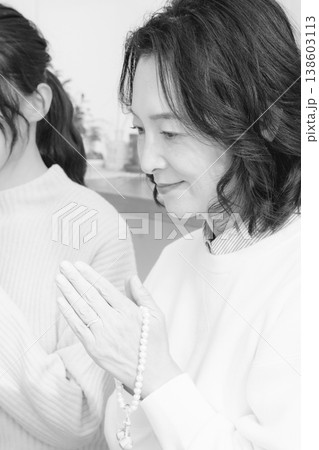 自宅で故人に祈りを捧げる母と娘(モノクロ) 自宅で故人に祈りを捧げる母と娘(モノクロ) 138603113