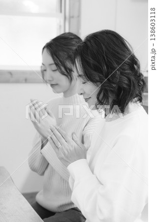 自宅で故人に祈りを捧げる母と娘(モノクロ) 自宅で故人に祈りを捧げる母と娘(モノクロ) 138603118