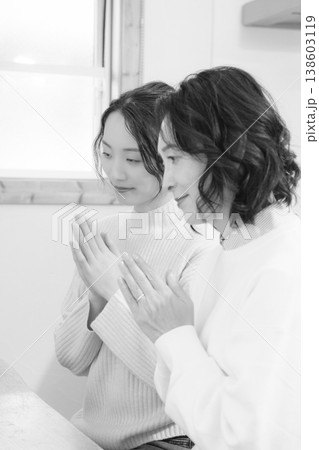 自宅で故人に祈りを捧げる母と娘(モノクロ) 自宅で故人に祈りを捧げる母と娘(モノクロ) 138603119