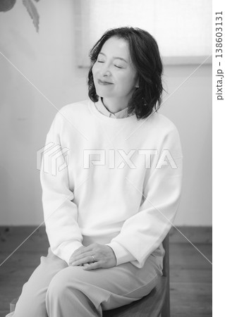 自宅で故人に祈りを捧げた後のミドル女性（モノクロ） 138603131