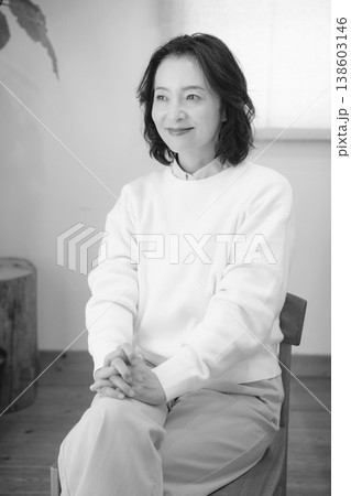 自宅で故人に祈りを捧げた後のミドル女性（モノクロ） 138603146