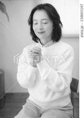 自宅で故人に祈りを捧げるミドル女性(モノクロ) 自宅で故人に祈りを捧げるミドル女性(モノクロ) 138603147