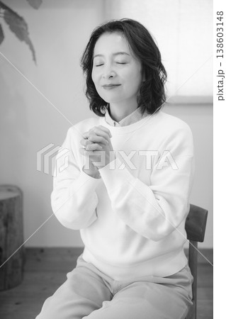 自宅で故人に祈りを捧げるミドル女性(モノクロ) 自宅で故人に祈りを捧げるミドル女性(モノクロ) 138603148