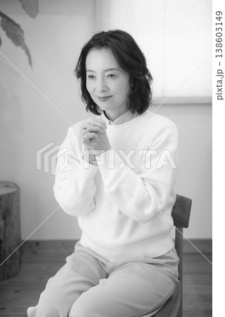自宅で故人に祈りを捧げるミドル女性（モノクロ） 138603149