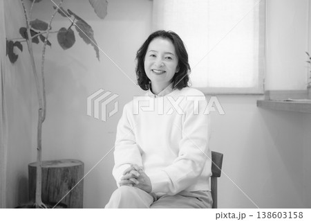 自宅で故人に祈りを捧げた後のミドル女性（モノクロ） 138603158